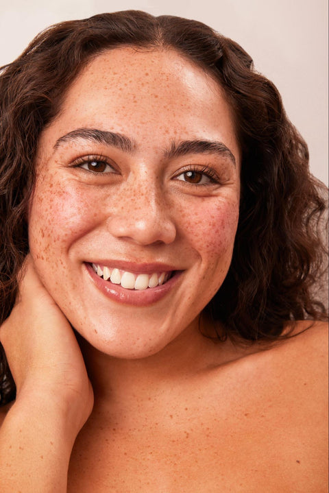 A woman with beautifully glowing skin smiles